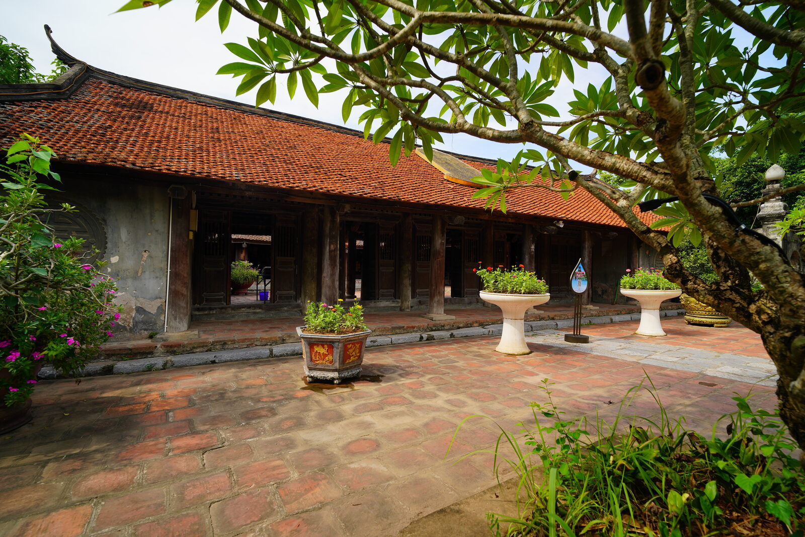 Dãy nhà hành lang mái ngói cổ bên khoảng sân lát gạch đỏ.